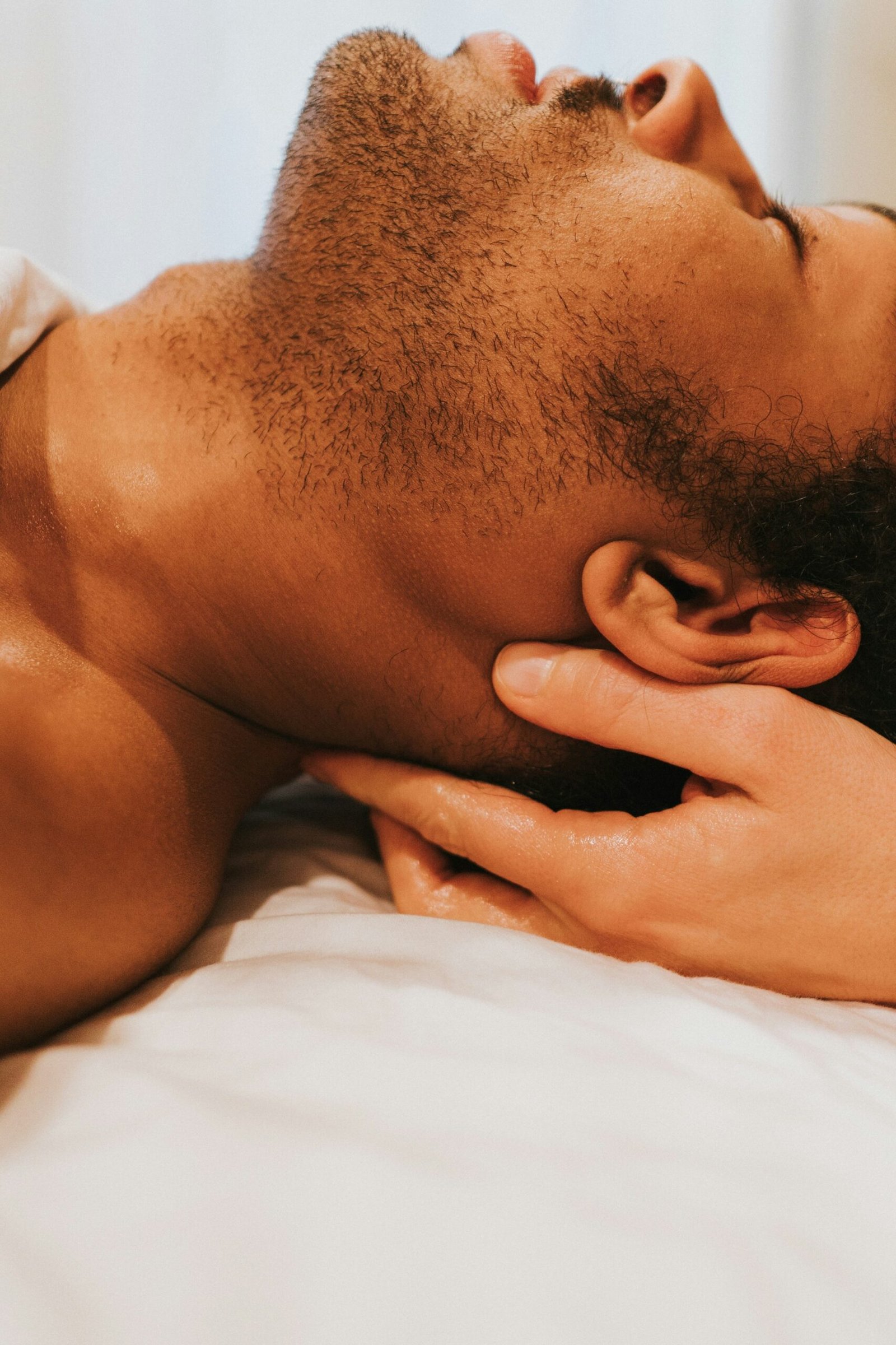 a man laying on top of a bed next to a window